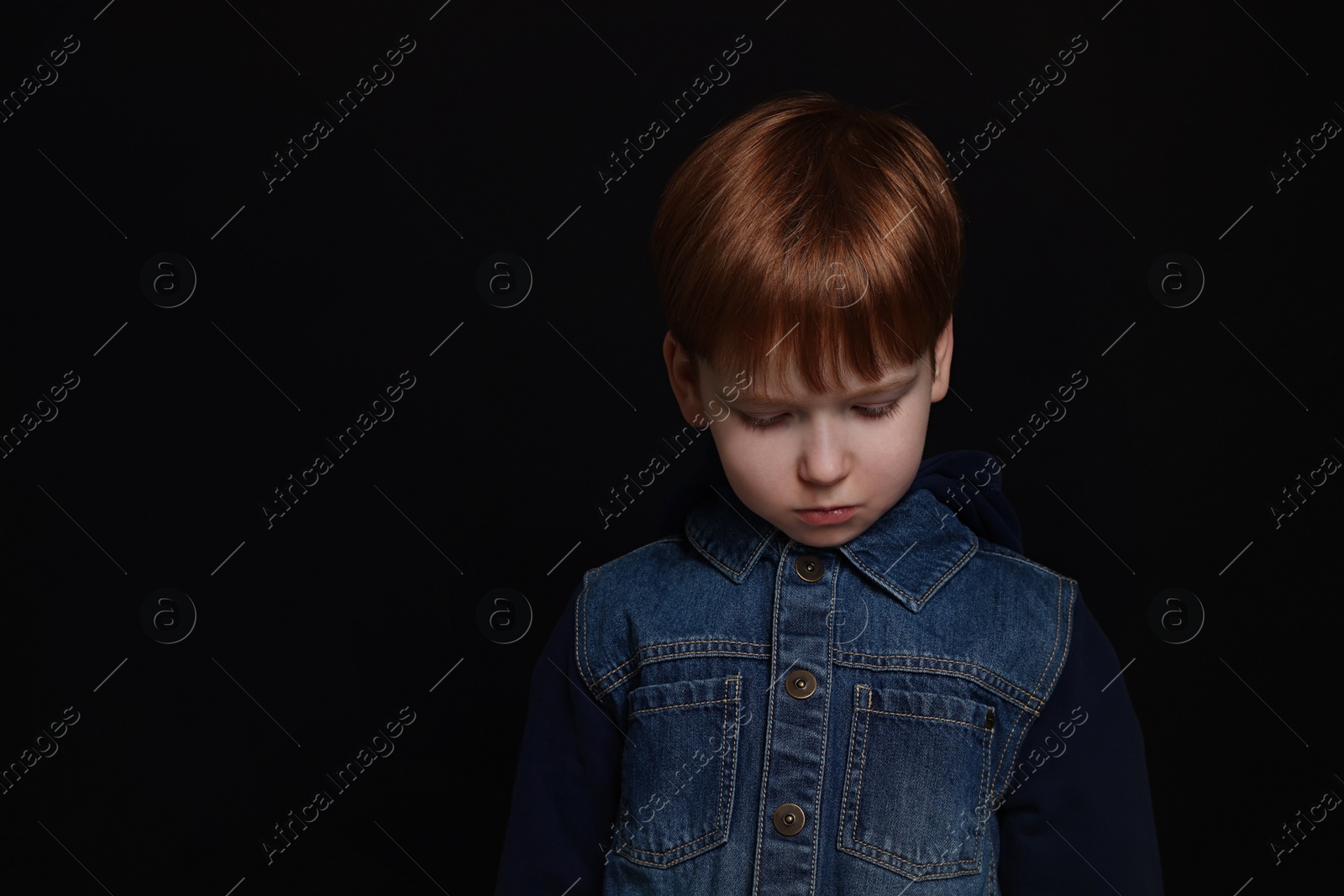 Photo of Upset boy on black background, space for text. Children's bullying