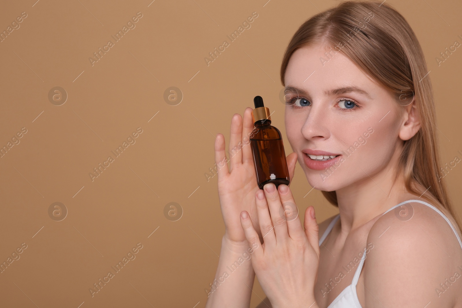 Photo of Beautiful young woman with essential oil on brown background. Space for text