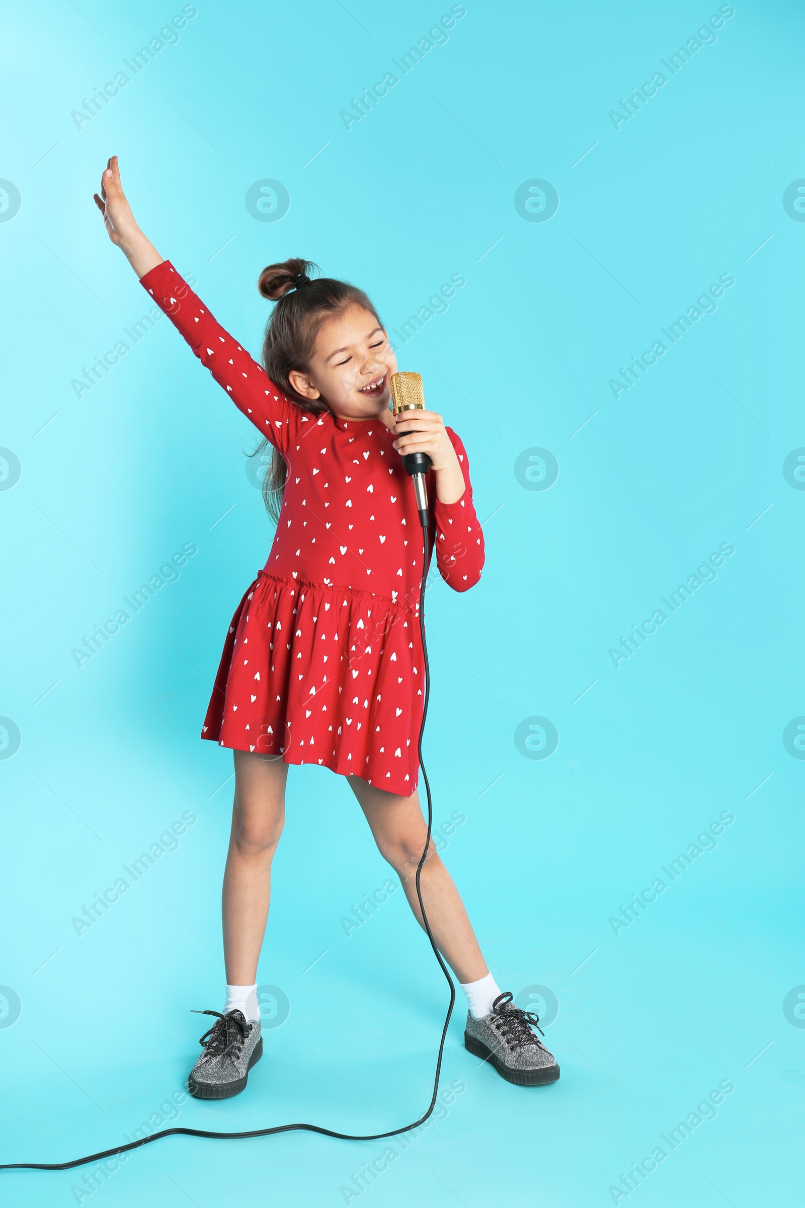 Photo of Cute funny girl with microphone on color background