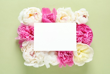 Photo of Fresh peonies and empty card on color background, flat lay with space for text