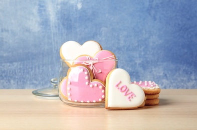 Photo of Glass jar and heart shaped cookies on wooden table. Valentine's day treat