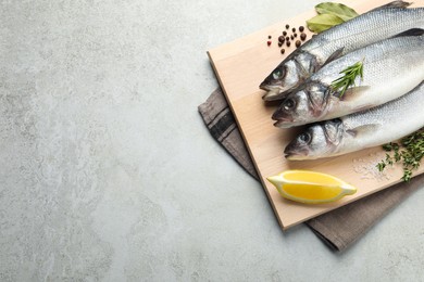 Photo of Tasty sea bass fish and spices on grey textured table, top view. Space for text