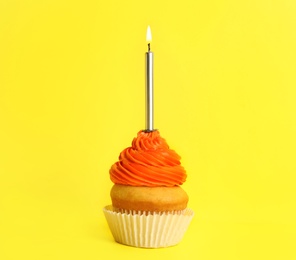 Birthday cupcake with candle on yellow background