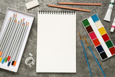 Photo of Flat lay composition with blank sketchbook on grey stone table. Space for text