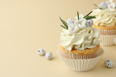 Tasty Easter cupcake with vanilla cream and candies on beige background, space for text