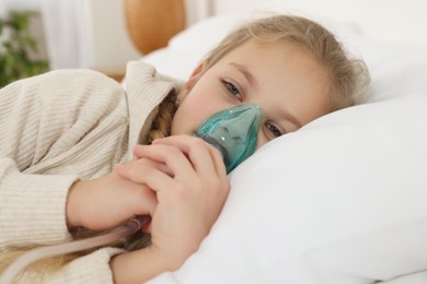 Photo of Little girl using nebulizer for inhalation in bedroom, closeup
