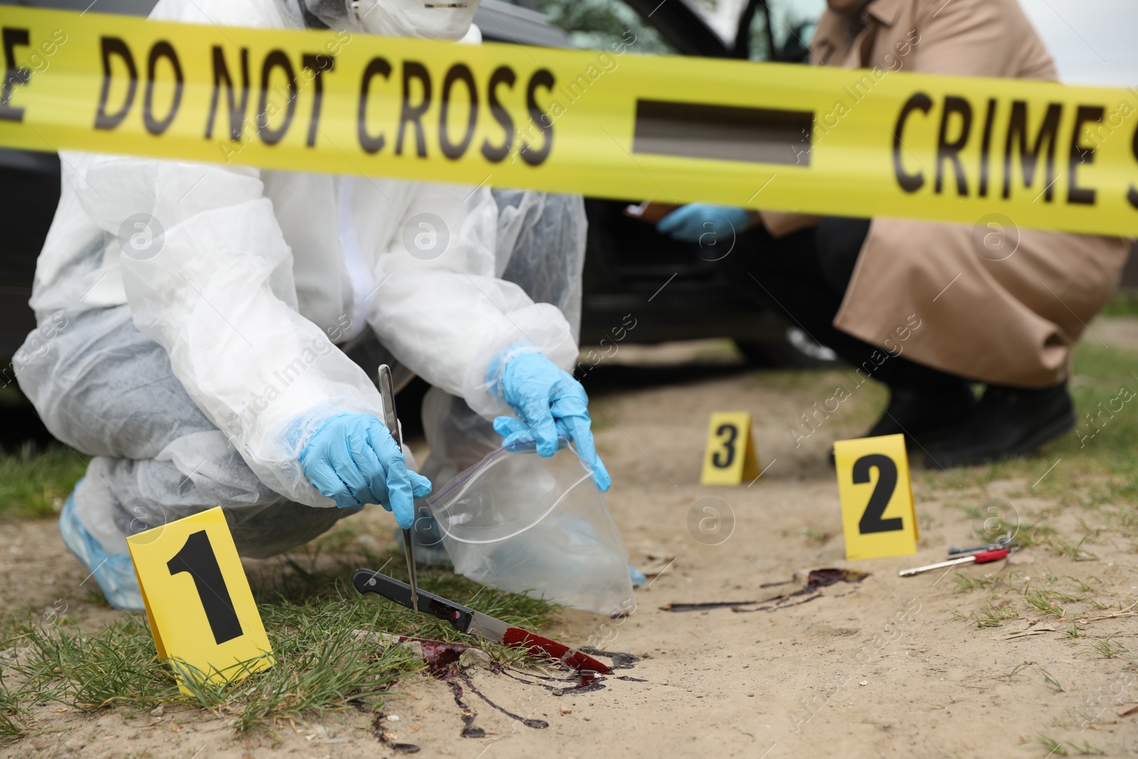 Photo of Investigator and criminologist working at crime scene outdoors, closeup
