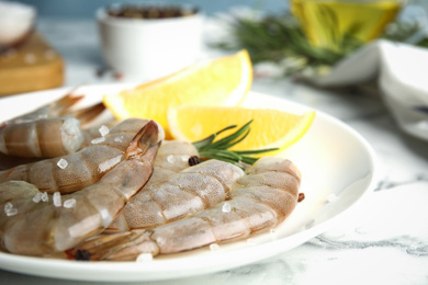 Photo of Fresh raw shrimps with lemon on plate, closeup