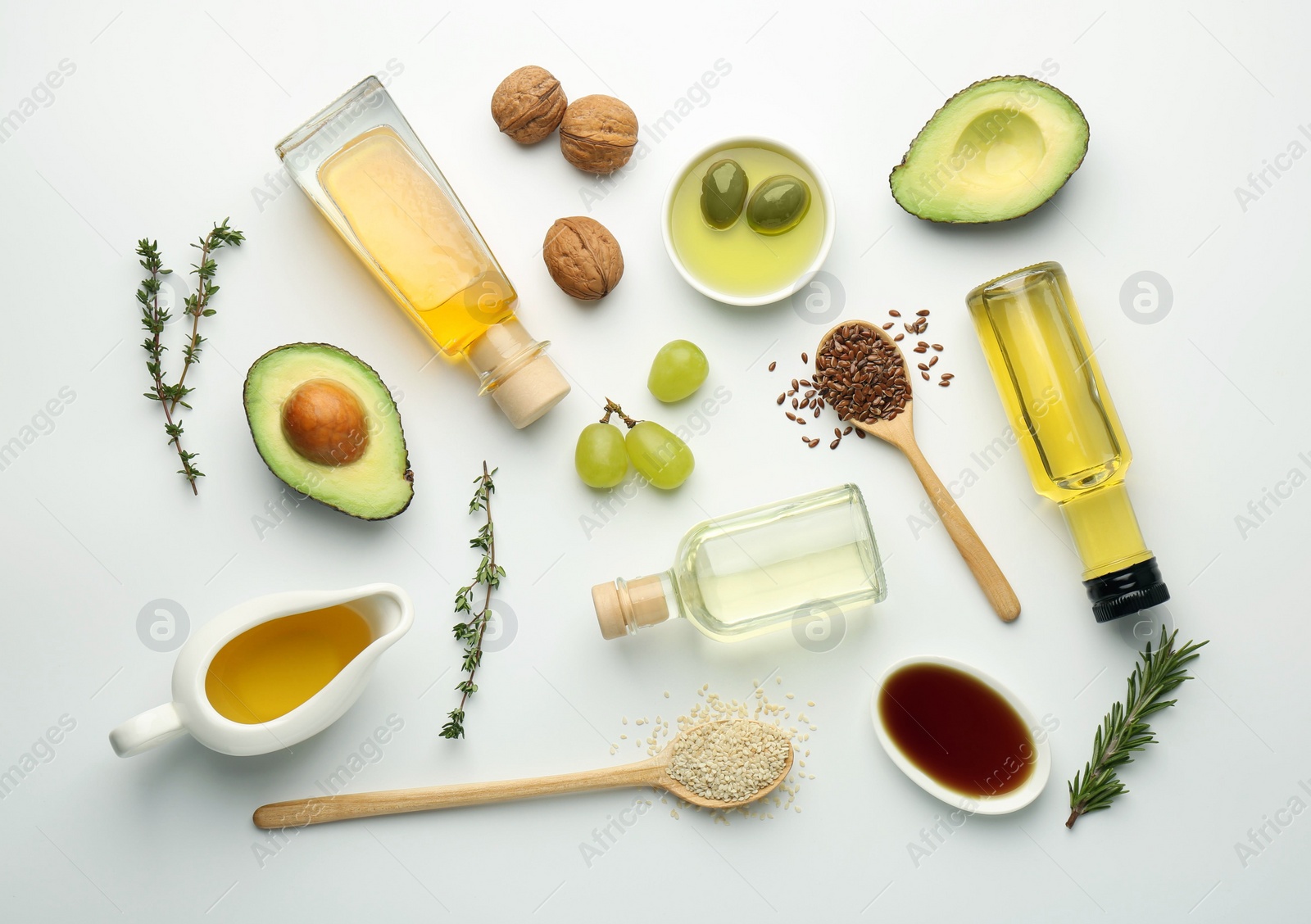 Photo of Vegetable fats. Different oils in glass bottles and ingredients on white table, flat lay