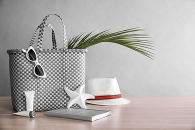 Beach objects on wooden table against color background