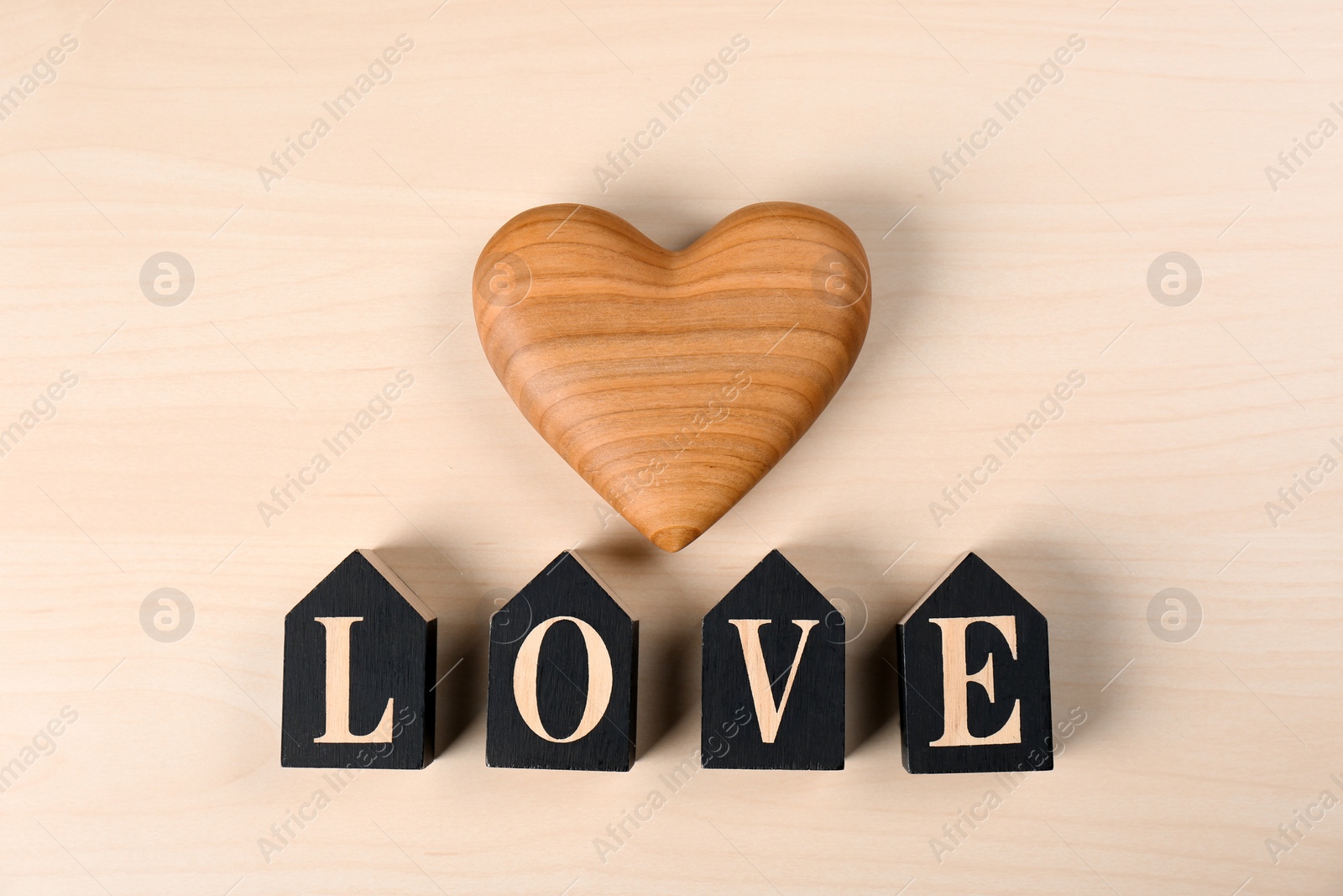 Photo of Word Love made of decorative letters and heart on wooden background, top view