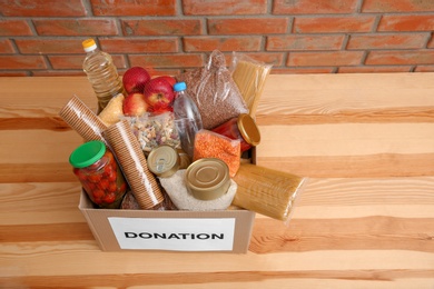 Photo of Donation box with food on wooden table, above view