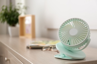 Photo of Modern portable fan on wooden table indoors, space for text. Summer heat