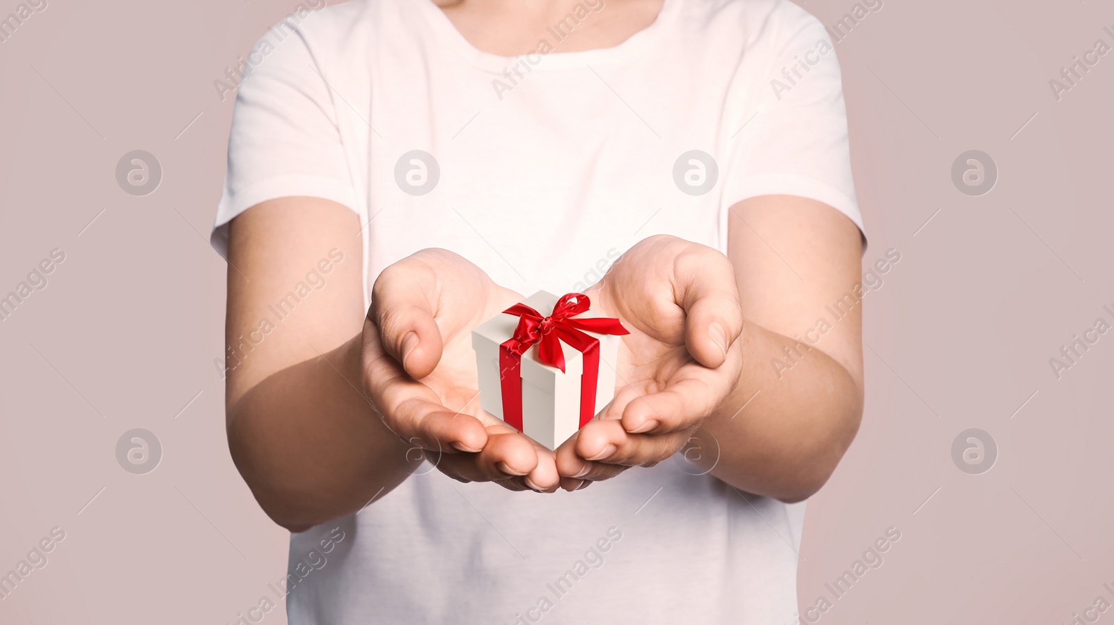 Image of Boxing day. Woman with gift on beige background, closeup 