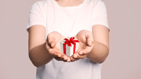 Boxing day. Woman with gift on beige background, closeup 