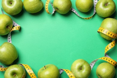 Photo of Frame made with ripe apples and measuring tape on green background, flat lay. Space for text