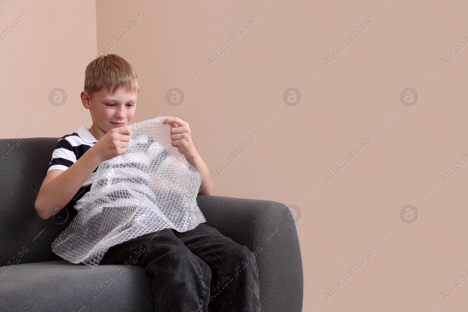 Photo of Boy popping bubble wrap at home, space for text. . Stress relief