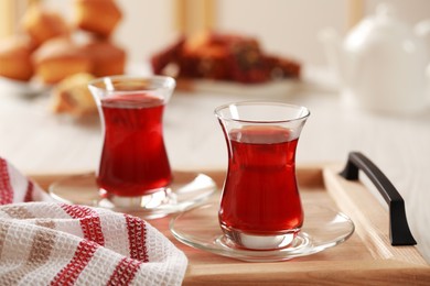 Photo of Glasses of traditional Turkish tea on wooden tray indoors