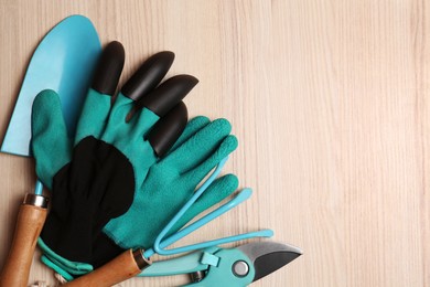 Photo of Gardening gloves and tools on wooden table, flat lay. Space for text