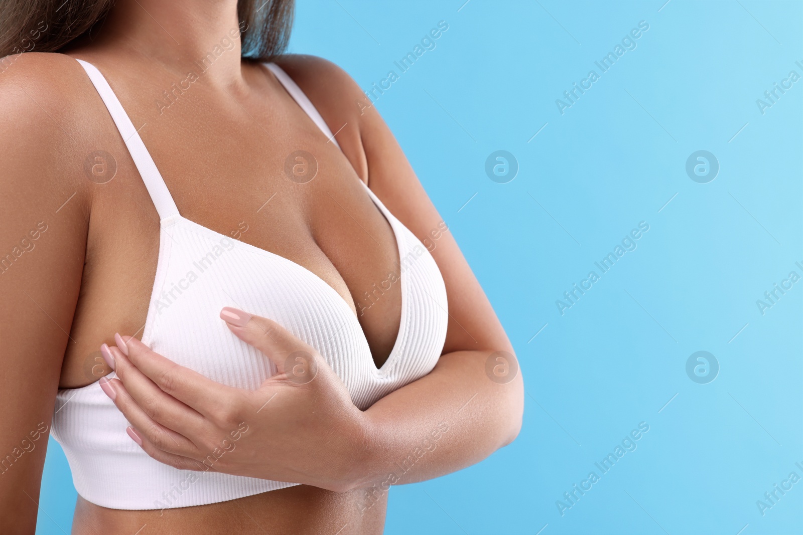 Photo of Woman with beautiful breast on light blue background, closeup. Space for text