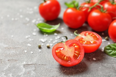 Cherry tomatoes with spice and basil on stone background. Space for text