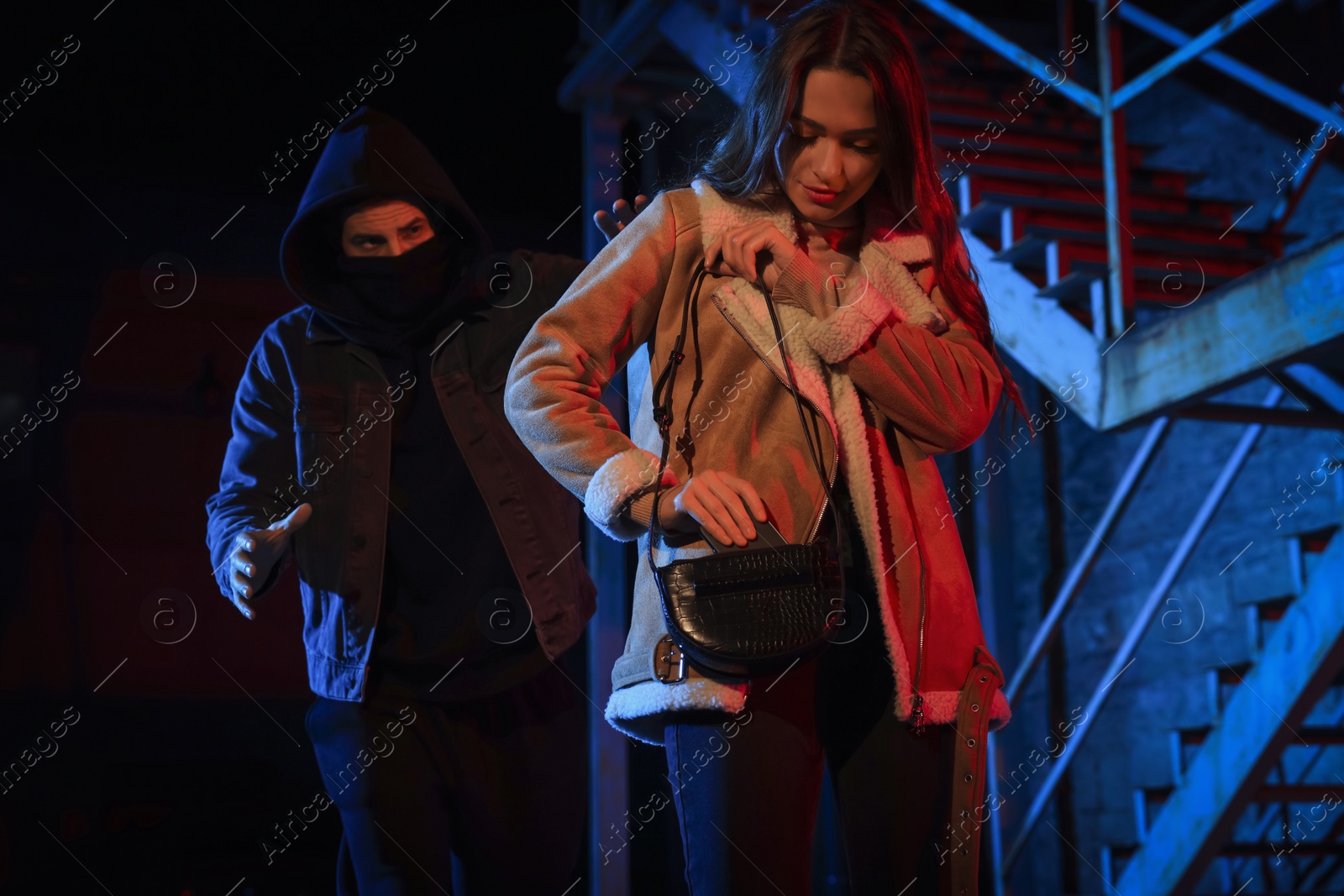 Photo of Criminal attacking young woman outdoors at night. Self defense concept