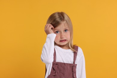 Photo of Portrait of embarrassed little girl on orange background