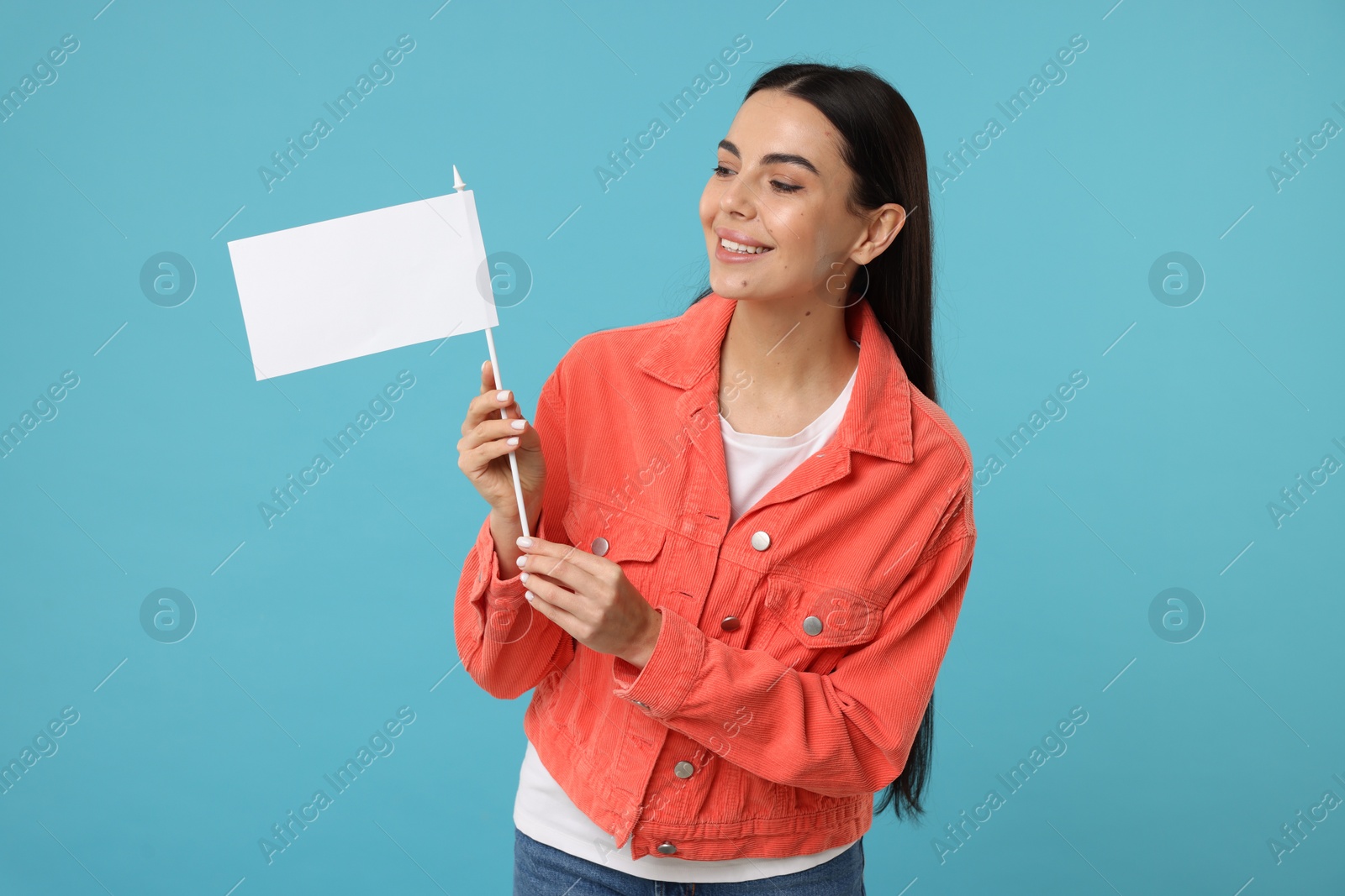 Photo of Happy young woman with blank white flag on light blue background. Mockup for design