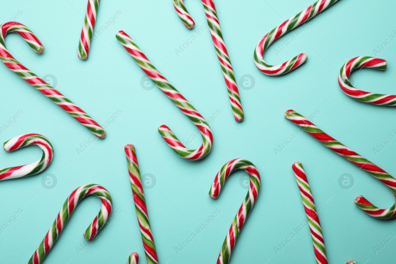 Photo of Many sweet Christmas candy canes on turquoise background, flat lay