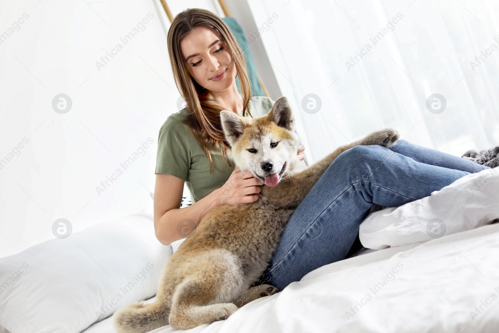 Photo of Young woman with adorable Akita Inu dog in bedroom