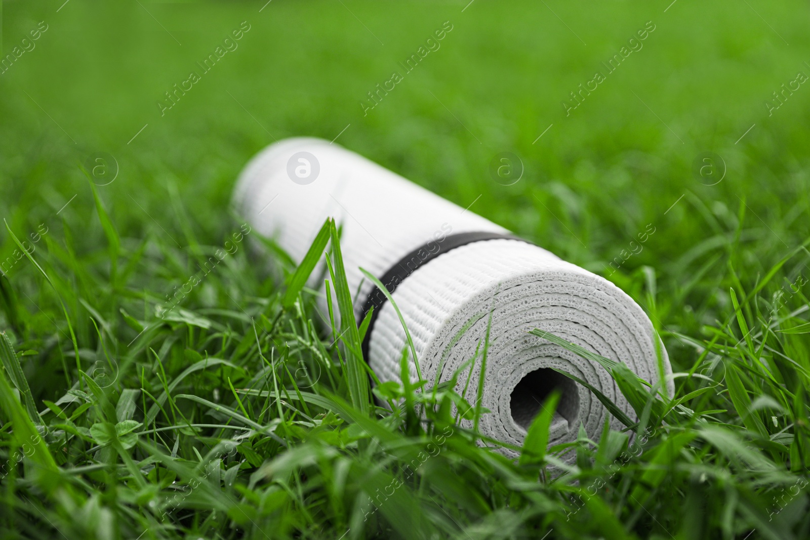 Photo of White karemat or fitness mat on green grass outdoors, closeup