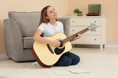 Teenage girl playing acoustic guitar in room