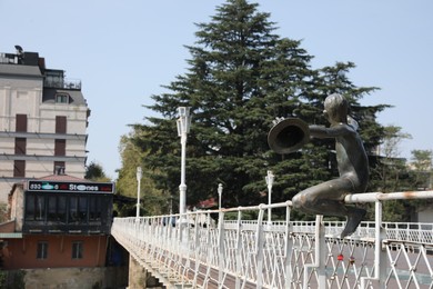 Photo of Kutaisi, Georgia - September 2, 2022: Sculpture of boy with hats on white bridge