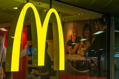 Photo of WARSAW, POLAND - AUGUST 05, 2022: Signboard with McDonald's logo on glass wall in restaurant