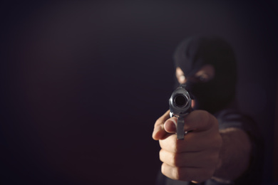 Professional killer on black background, focus on gun. Space for text