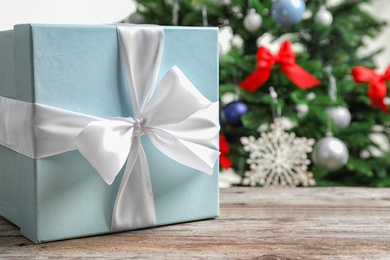 Photo of Beautiful gift box and blurred Christmas tree on background