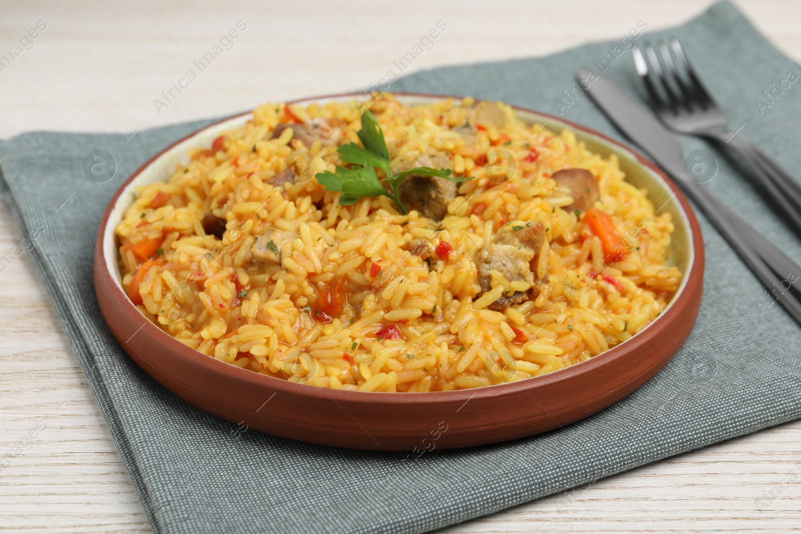 Photo of Delicious pilaf with meat served on white wooden table, closeup