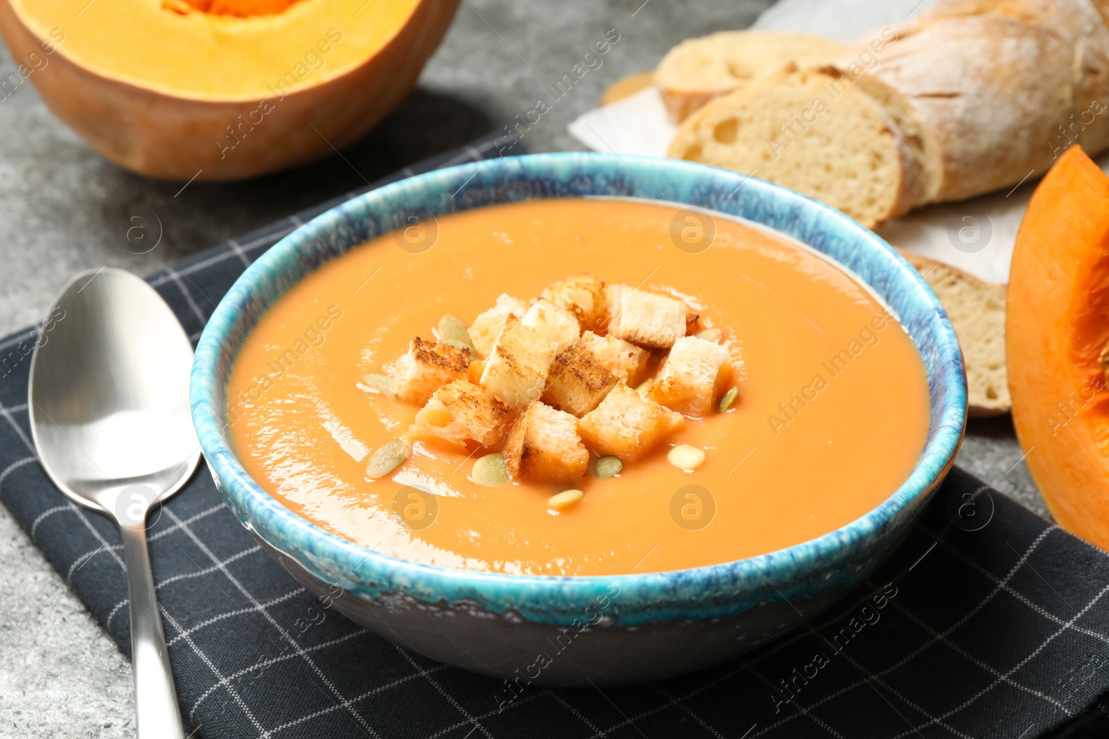 Photo of Tasty creamy pumpkin soup with croutons and seeds in bowl on table
