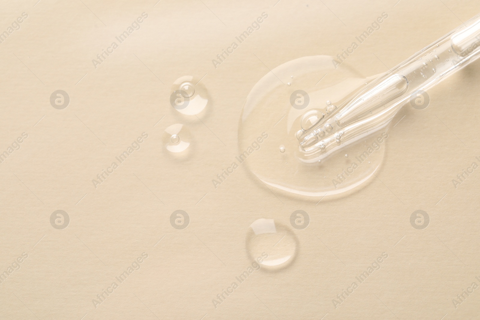 Photo of Glass pipette and transparent liquid on beige background, top view. Space for text