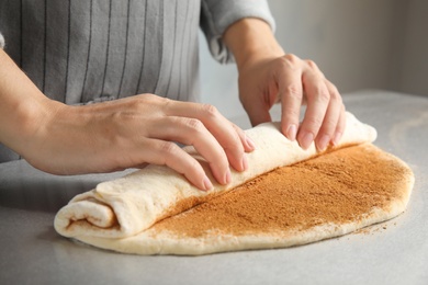 Photo of Woman making cinnamon rolls at table, closeup