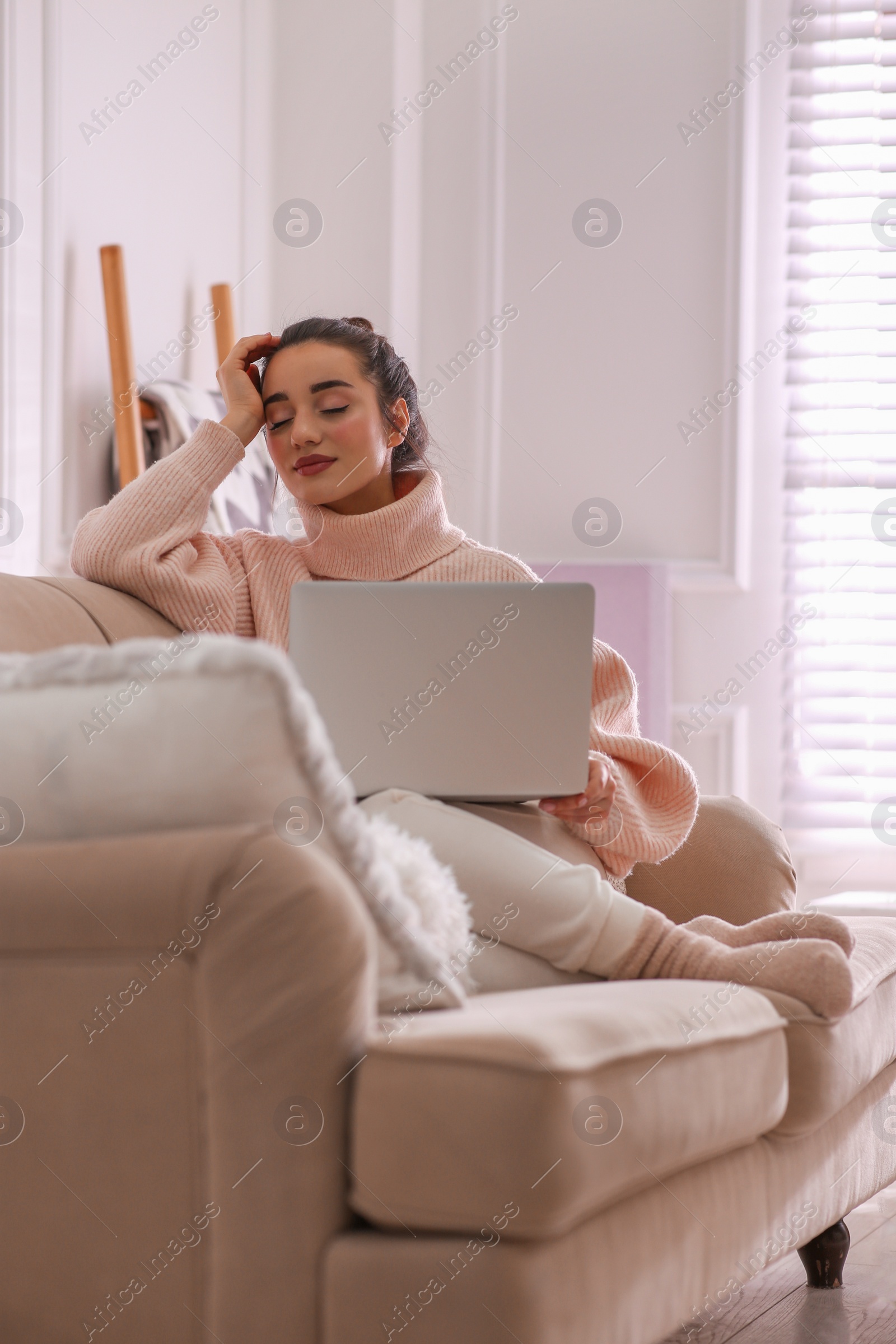 Photo of Beautiful young woman with laptop relaxing at home. Cozy atmosphere