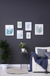 Photo of Beautiful paintings of leaves on black wall in living room interior