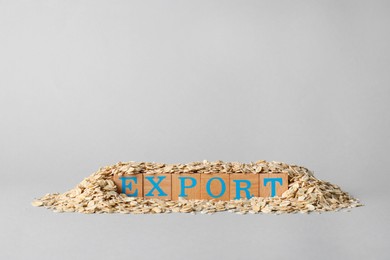 Photo of Pile of oatmeal and wooden cubes with word Export on grey background, space for text