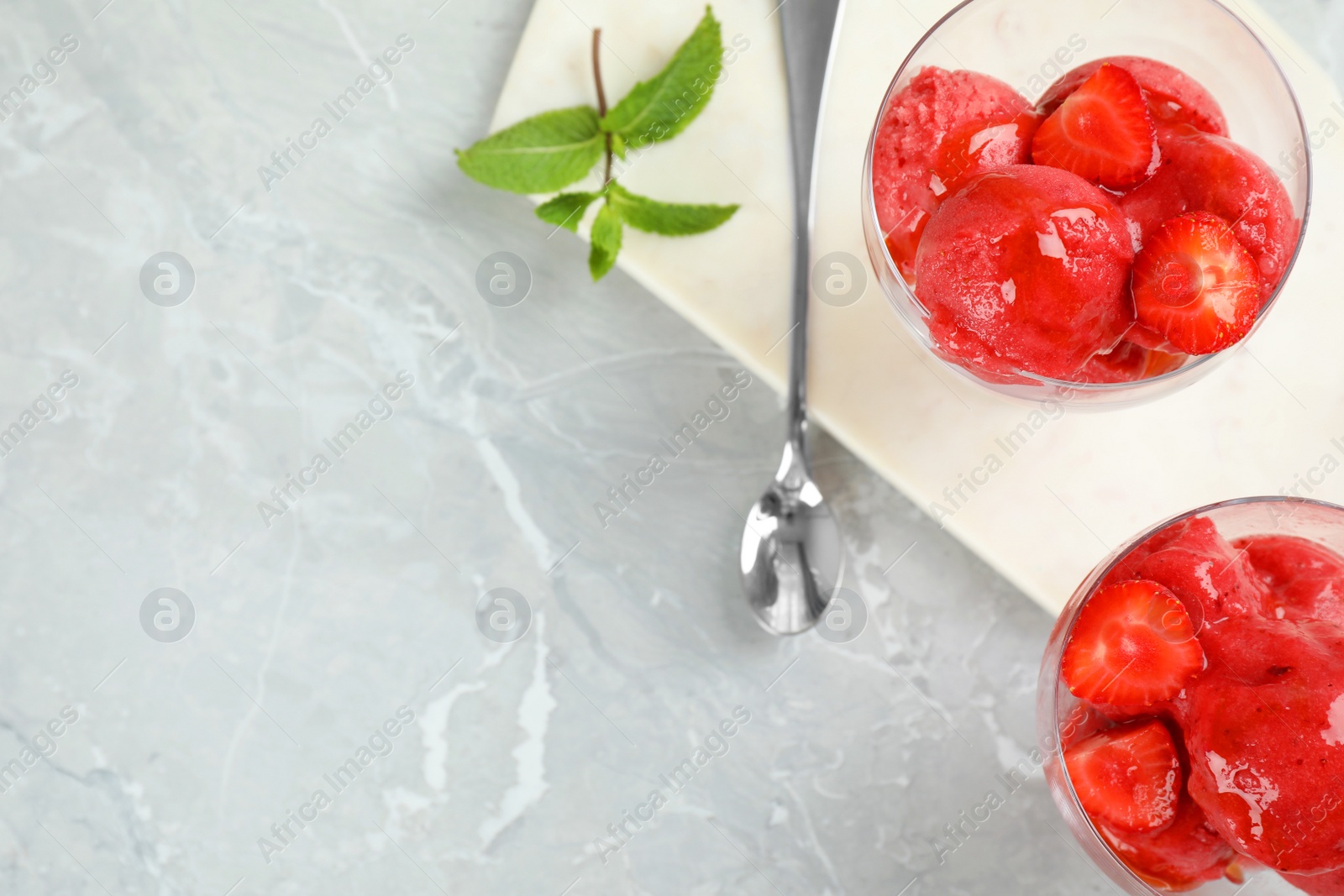 Photo of Flat lay composition with delicious strawberry ice cream on grey marble table, space for text