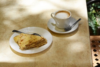 Photo of Piece of delicious cake and coffee on beige table