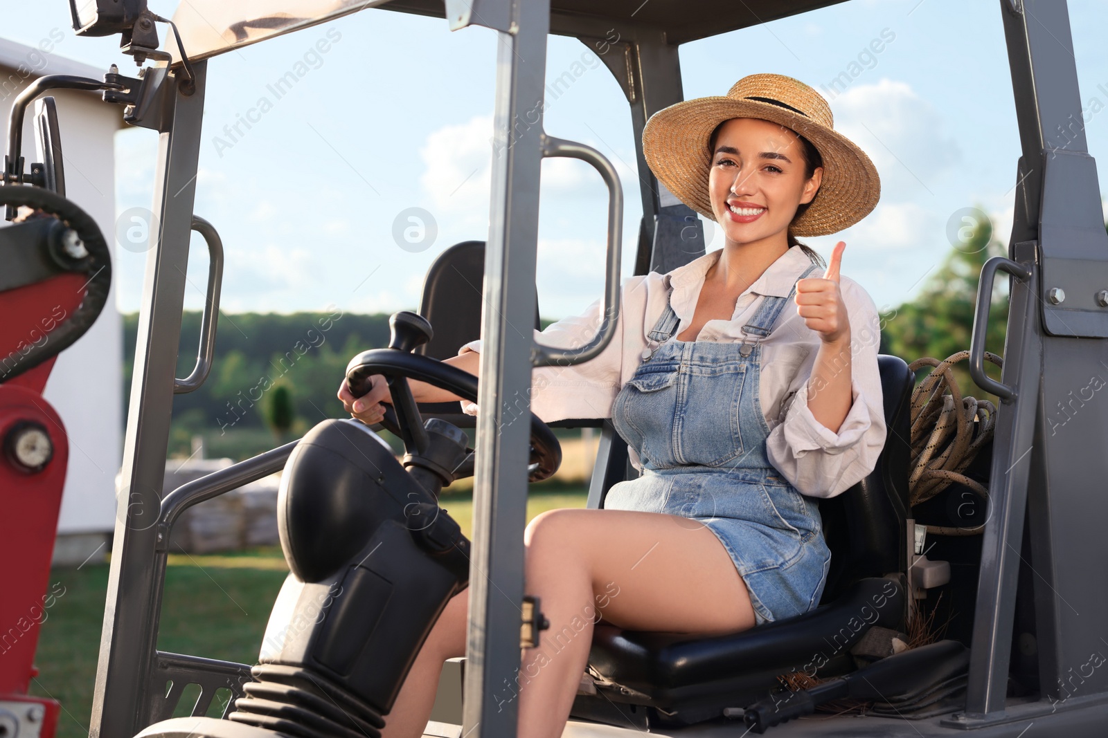 Photo of Smiling farmer driving loader and showing thumb up outdoors