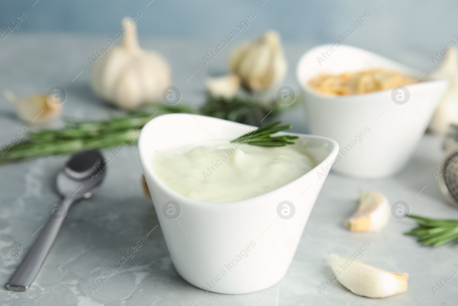 Photo of Composition with bowl of garlic sauce on grey table