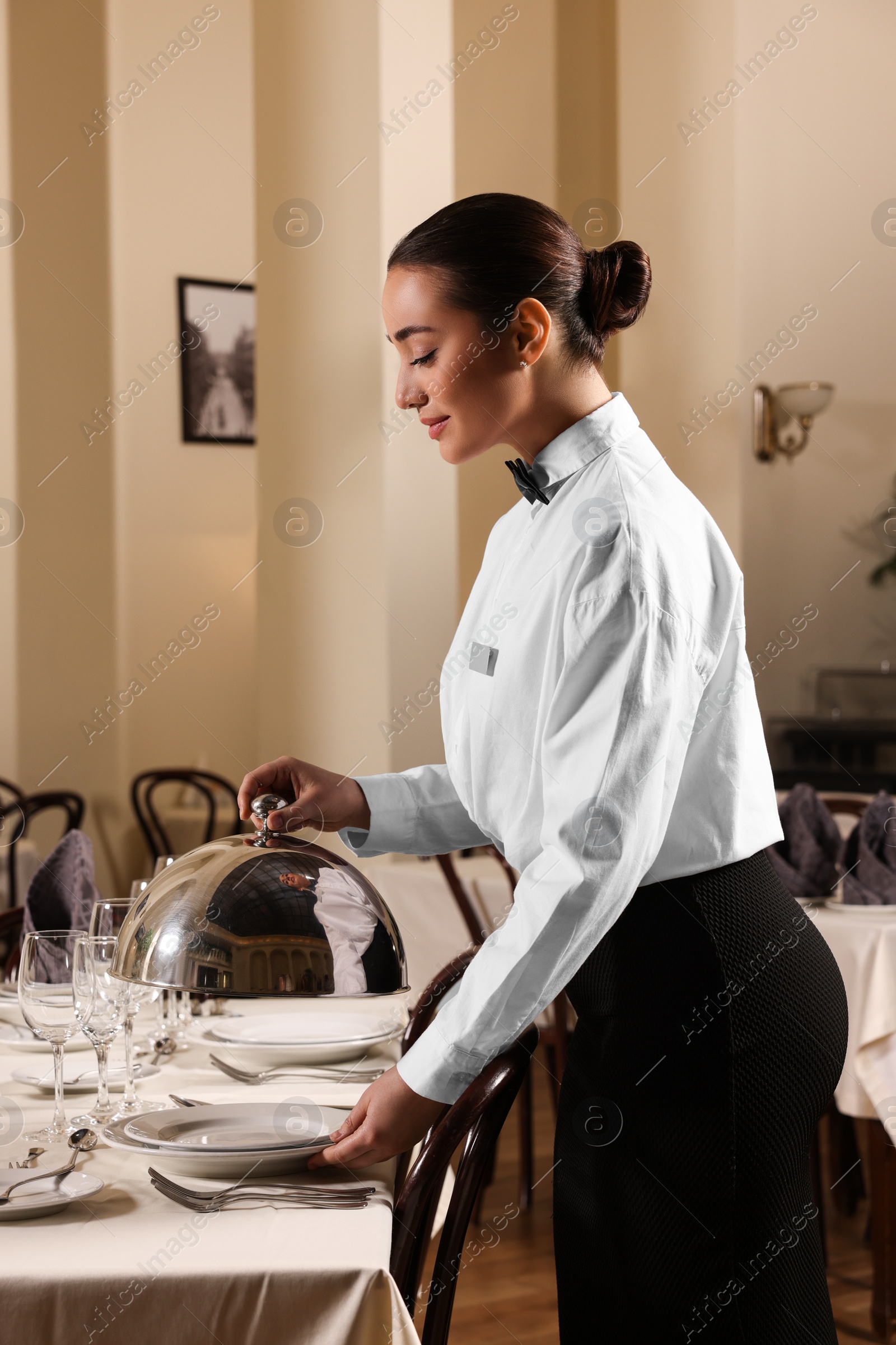 Photo of Woman setting table in restaurant. Professional butler courses