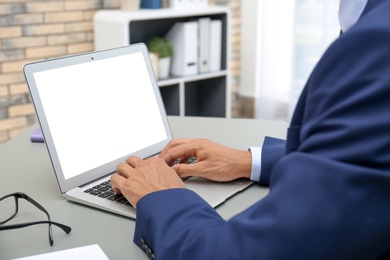 Photo of Man in office wear using laptop at table indoors