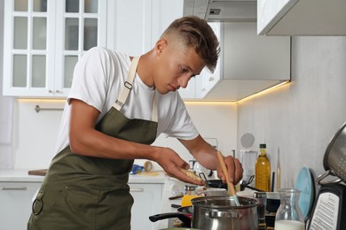 Photo of Man putting grated cheese into saucepan in messy kitchen. Many dirty dishware and utensils countertop